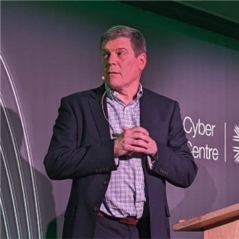 Photo of a man wearing a blazer presenting on stage